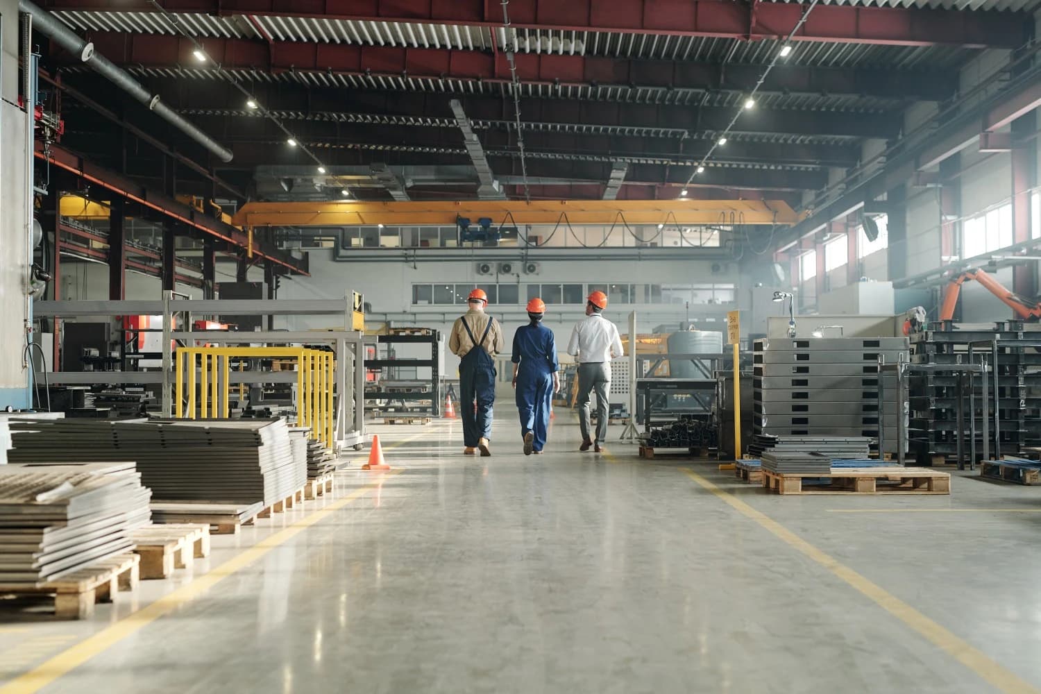 Tres trabajadores caminando dando la espalda en el interior de una bodega de materiales de construcción