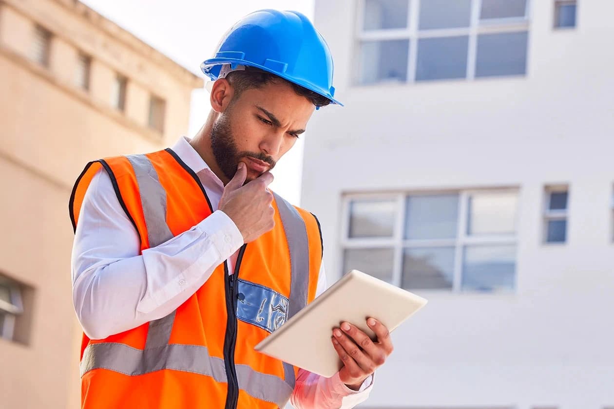 Hombre con casco de seguridad en una fabrica viendo un plano de construcción en una tablet